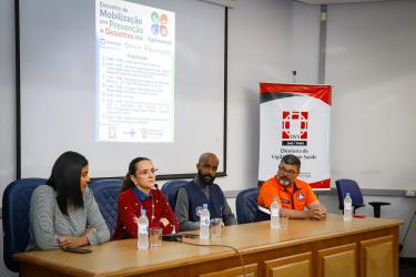 Mesa de abertura com a Coord. Assepla SMS, Kelma Nunes Soares, dir. da DVS, Aline Medeiros, o coord. Defesa Civil de POA, Cel. Evaldo Rodrigues e demais autoridades.